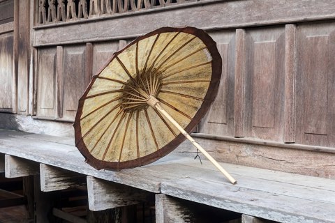 Beige and brown oil paper umbrella on the edge of a wooden house in Luang Prabang Laos