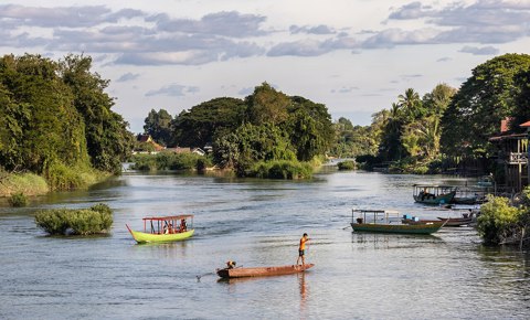 Fisherman and pirogue sailing on the Mekong a sunny afternoon in Don Det Laos